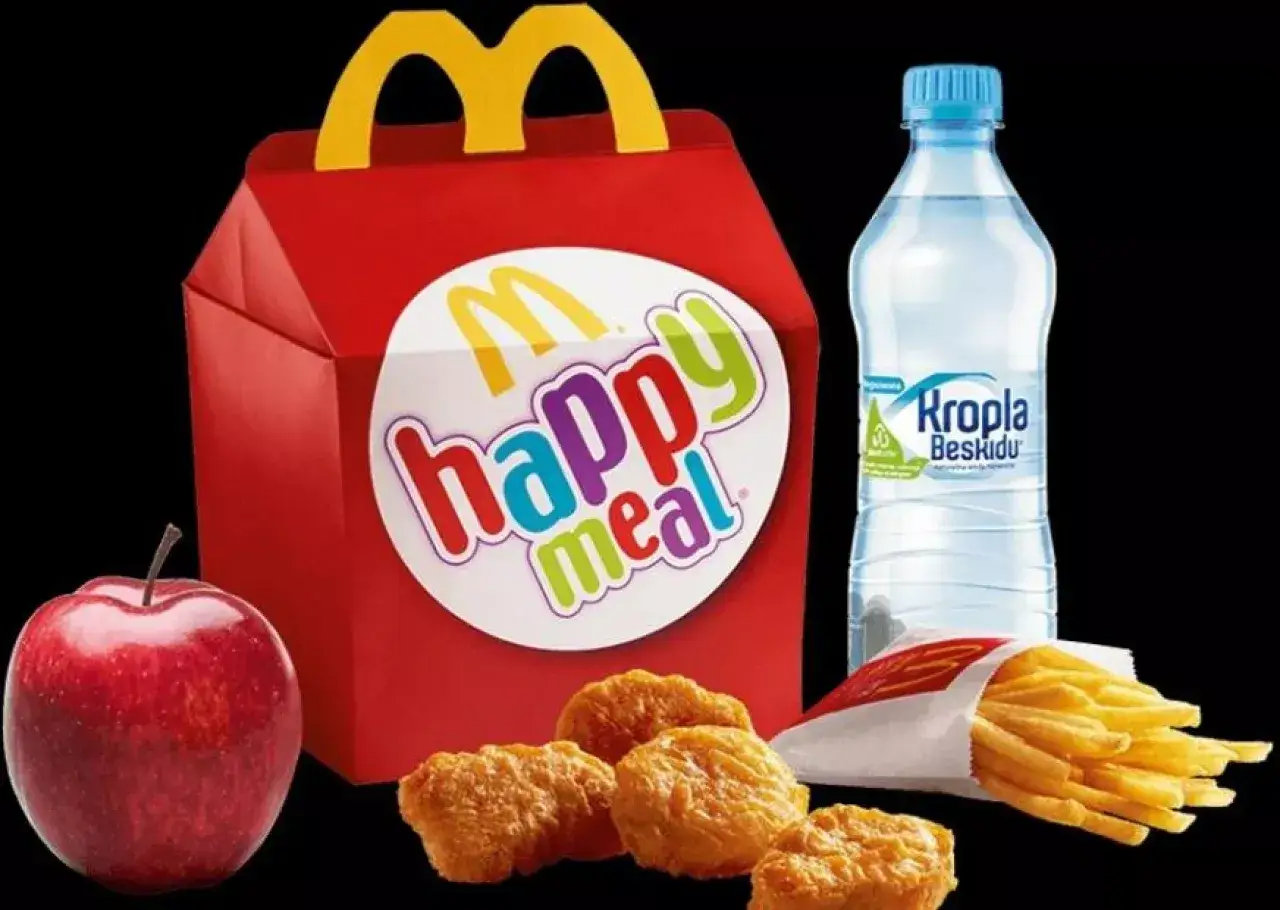Zestaw happy meal McDonald's: czerwone pudełko z logo, nuggetsy, frytki, jabłko i butelka wody.