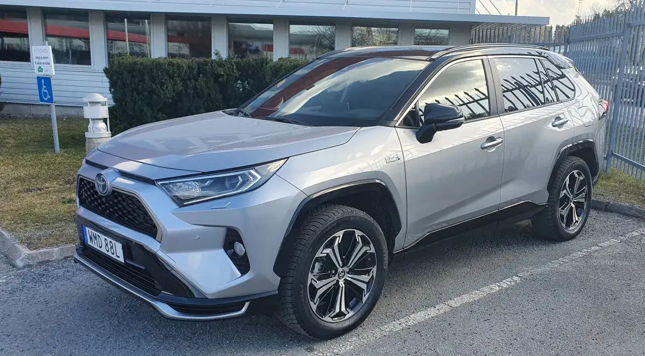 Silver Toyota RAV4 laddhybrid testbil parkerad utanf&ouml;r en byggnad.