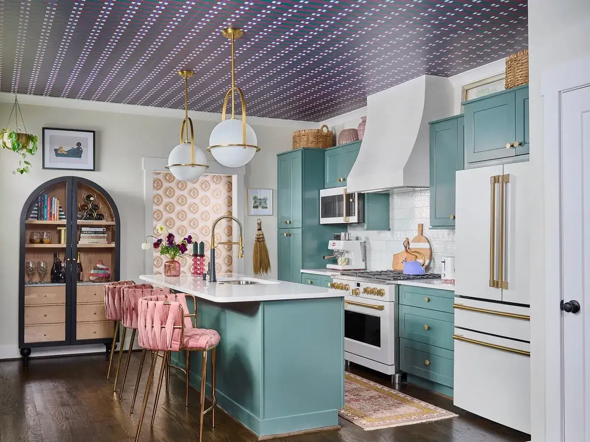 Eine Küche in Aqua-Blau mit rosa Barhockern und goldenen Akzenten. Welche Farbe passt zu Aqua-Blau? Hier sehen wir Rosa und Gold als harmonische Ergänzung.