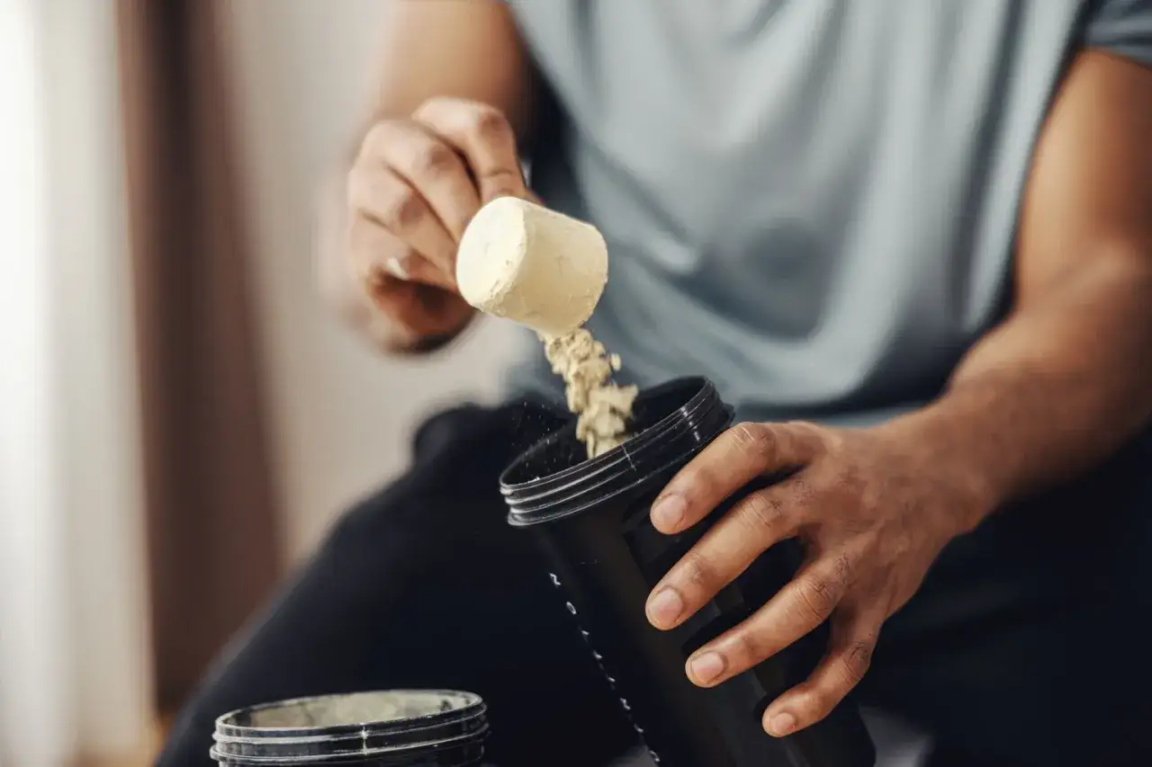 Hombre añadiendo polvo a un bote. Ideal para saber bcaa cuando tomar y optimizar tu entrenamiento.