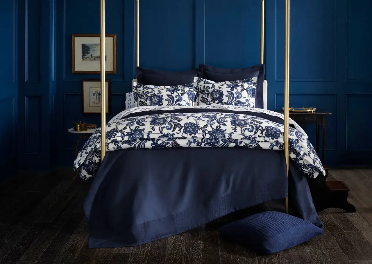Elegante camera da letto blu con letto a baldacchino, biancheria da letto floreale e pareti pannellate.