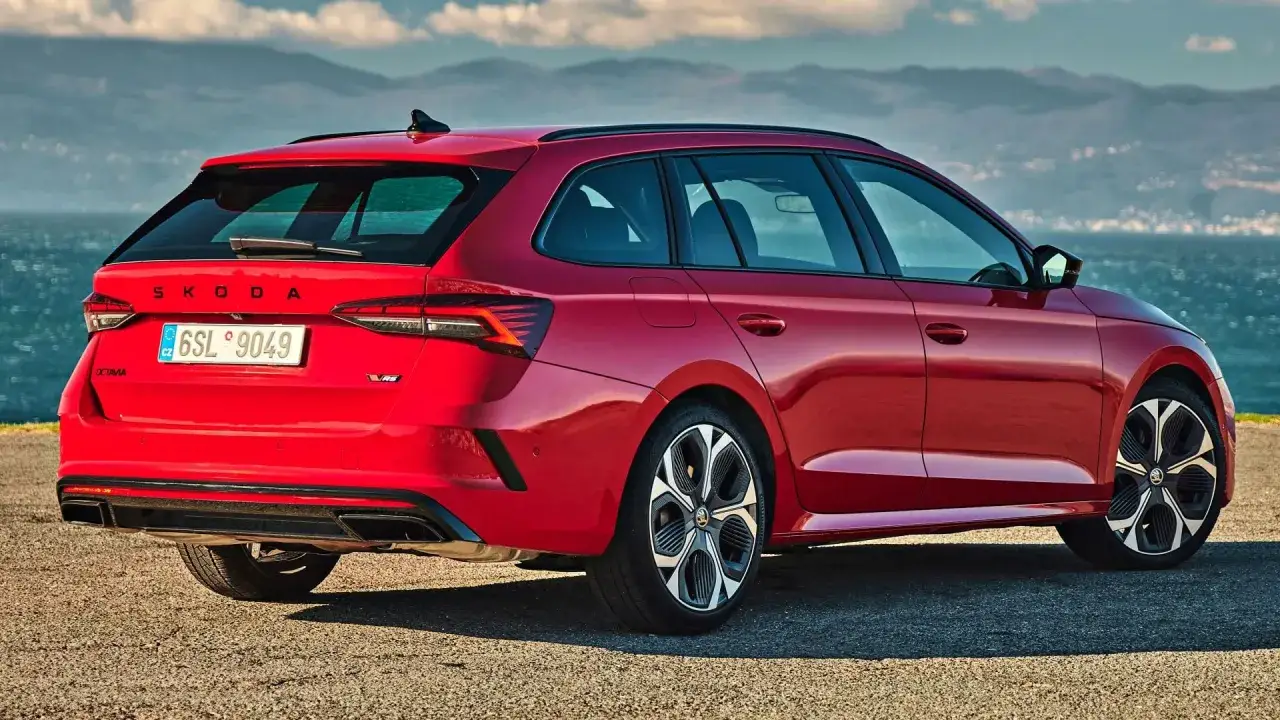 Czerwona Skoda Octavia 2026 z nowoczesnymi światłami i felgami stoi na tle morza i gór.