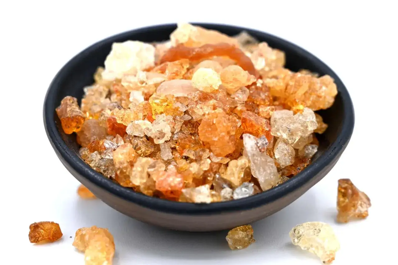 Grains ambr&eacute;s et translucides dans un bol, repr&eacute;sentant qu'est-ce que la gomme arabique, un ingr&eacute;dient naturel aux multiples usages.