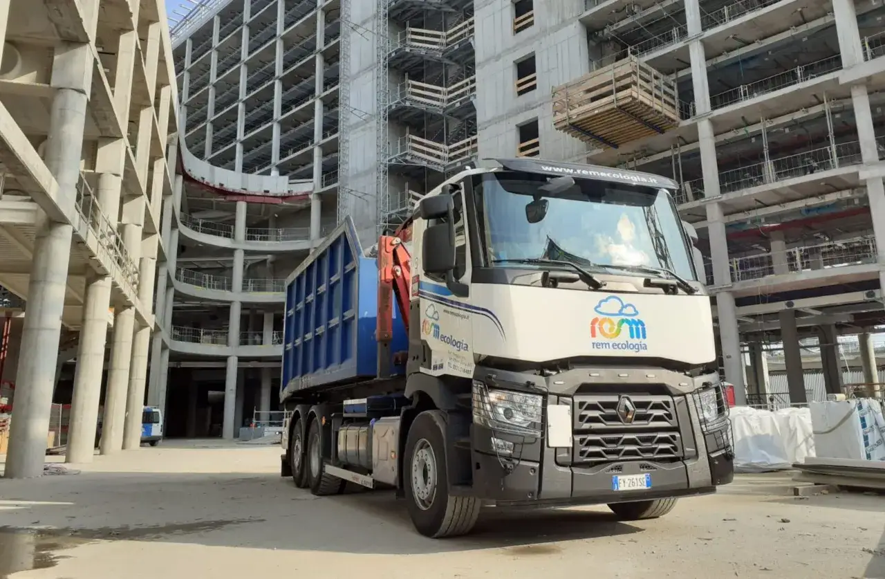 Camion per lo smaltimento rifiuti edili da privato in cantiere. Struttura in cemento armato in fase di costruzione.
