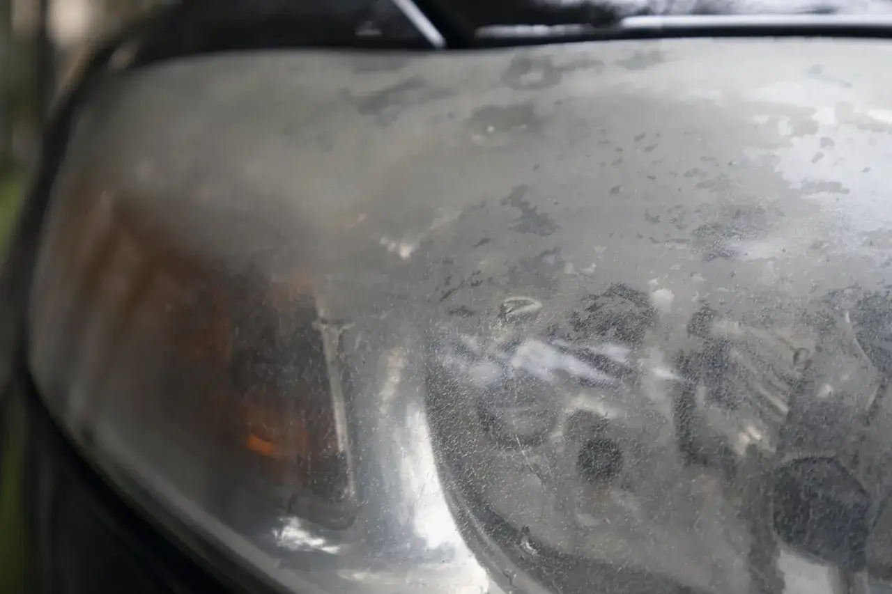 Widoczne mikropęknięcia na reflektorze samochodu, które nadają mu matowy, zniszczony wygląd.