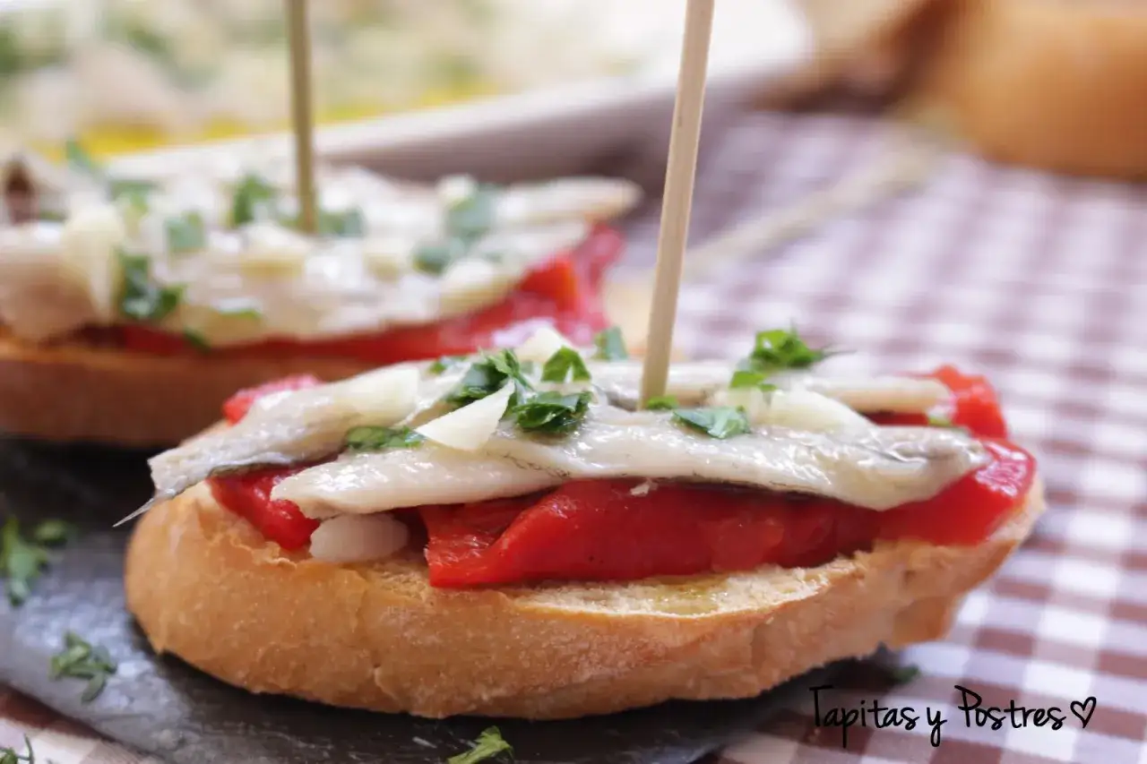 Deliciosos boquerones en vinagre sobre pan tostado con pimientos asados y perejil. ¡Un bocado perfecto!
