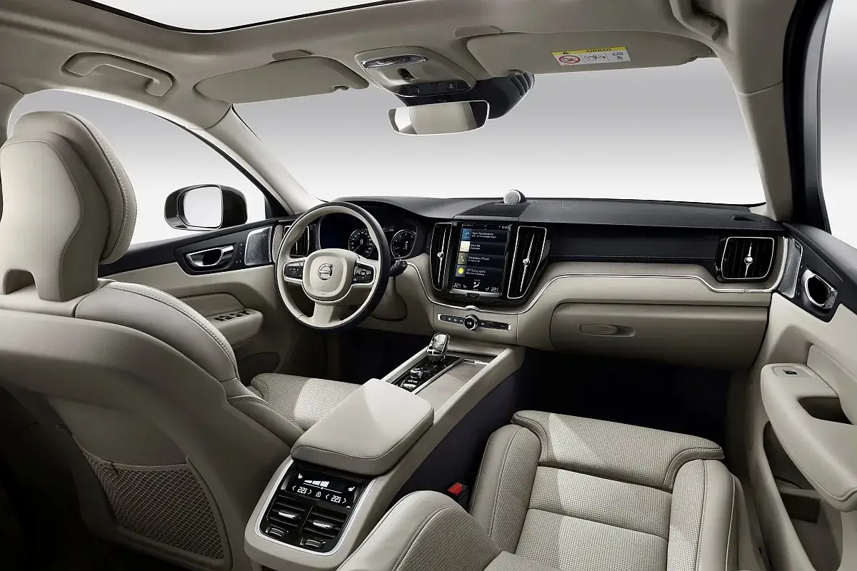 Wnętrze Volvo XC60 2025: jasne, skórzane fotele, duży ekran multimedialny i nowoczesna deska rozdzielcza.