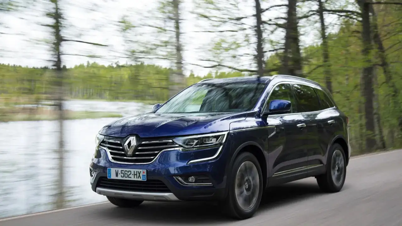 Bl&aring; Renault Koleos k&ouml;r l&auml;ngs en skogsv&auml;g. Trots att det &auml;r en fin dag, verkar det finnas ett **Renault Koleos problem** med att bilen inte verkar vara helt i fokus.