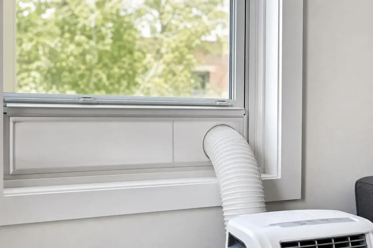 Climatiseur mobile r&eacute;versible en mode chauffage, avec tuyau d'&eacute;vacuation passant par la fen&ecirc;tre. Confort toute l'ann&eacute;e.