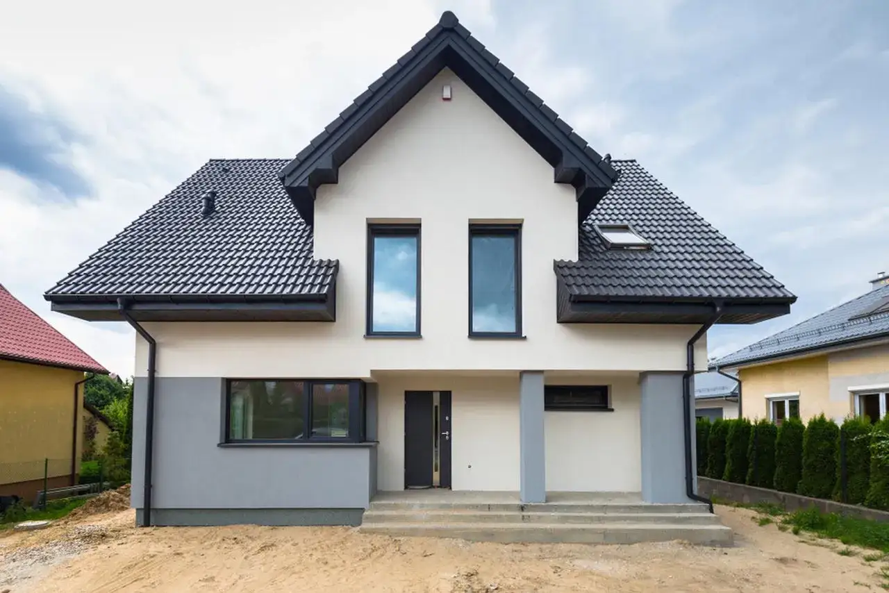 Nowy dom 120m2 czeka na wykończenie. Zastanawiasz się, ile kosztuje remont domu 120m2? Ten nowoczesny budynek z szarymi akcentami i czarnym dachem to potencjalny projekt.