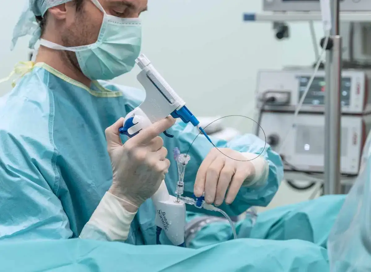 Lekarz w masce i rękawiczkach wykonuje biopsję gruczołu krokowego, używając specjalistycznego pistoletu do pobierania próbek.