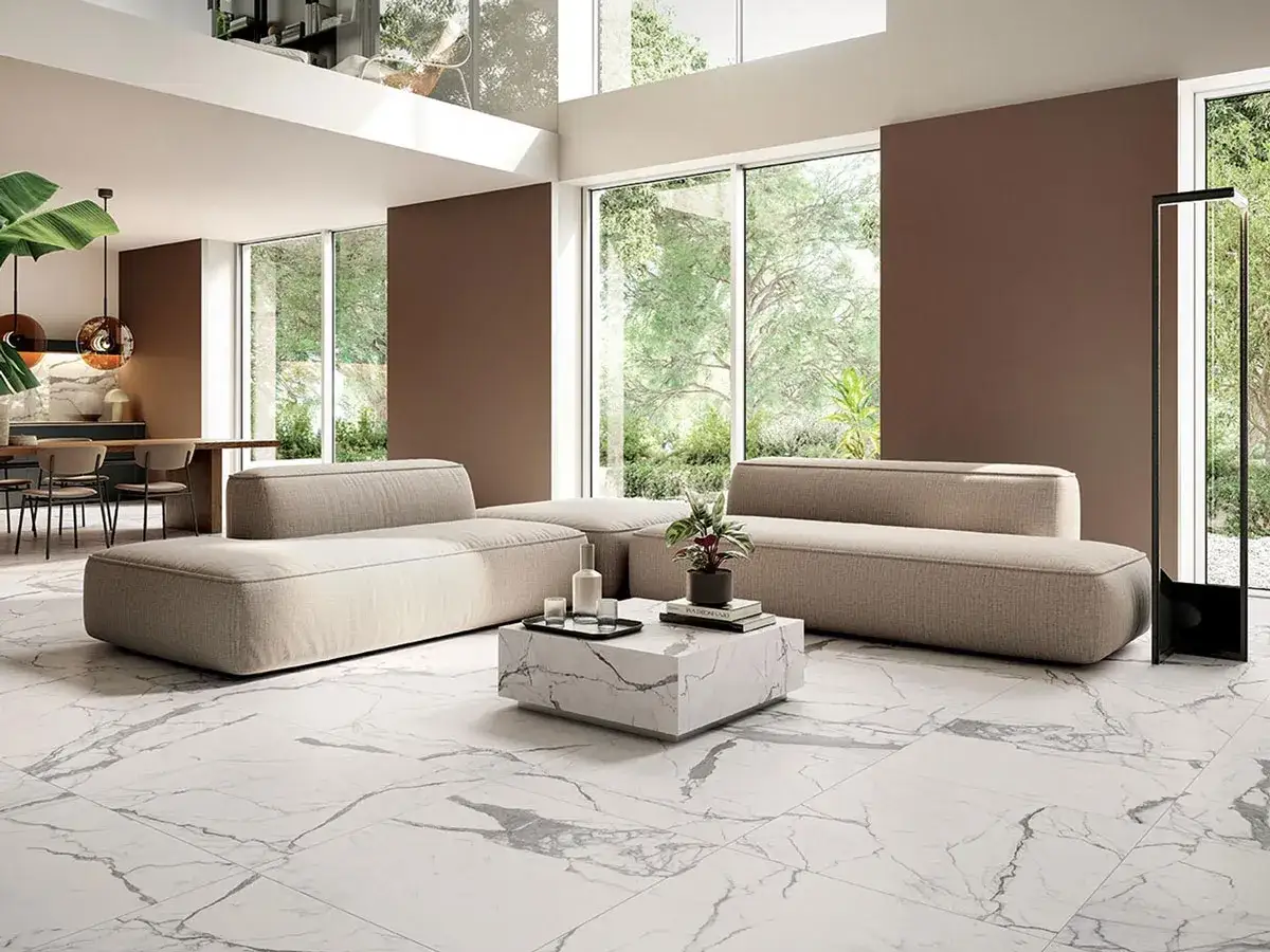 Soggiorno moderno con divani beige e un tavolino in uno dei tipi di marmo bianco più eleganti, con venature grigie che richiamano il pavimento.