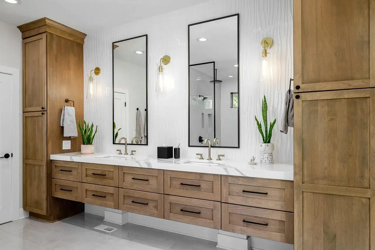 Elegante baño con doble lavabo, encimera de mármol, gabinetes de madera y una lámpara espejo baño.