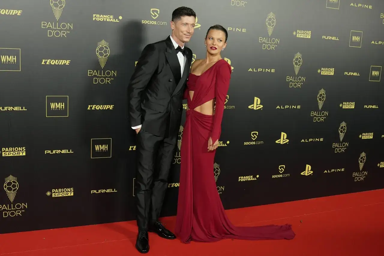 Robert Lewandowski w eleganckim garniturze i Anna Lewandowska w czerwonej sukni na gali Złotej Piłki.