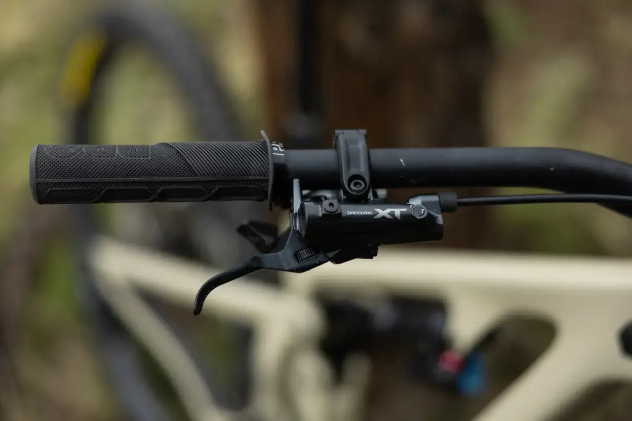 Close-up of a mountain bike handlebar with a Deore XT brake lever. The brake fluid viscosity is crucial for smooth operation.