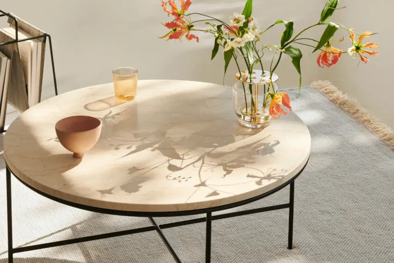 Elegante Ikebana-Beispiele auf einem Marmortisch, mit einem Glas und einer Schale.