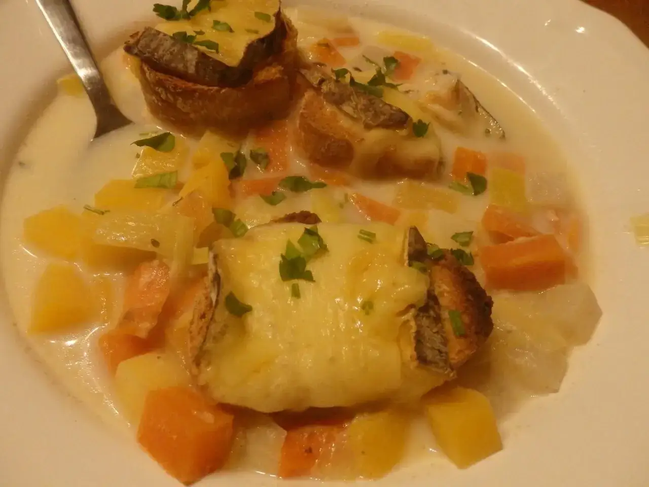 Une généreuse soupe savoyarde avec des croûtons gratinés au fromage fondant, des carottes et des pommes de terre coupées en dés.