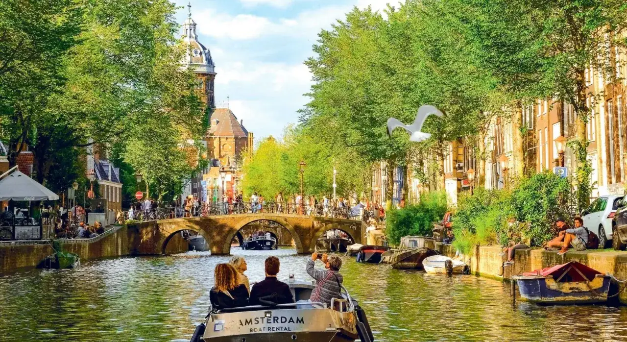 Rejs po kanałach Amsterdamu, gdzie zielone drzewa i zabytkowe kamienice tworzą malownicze holandia atrakcje.