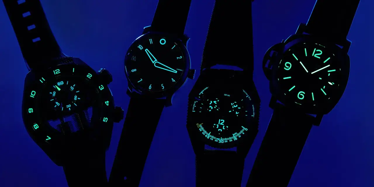 Quattro orologi con quadranti luminosi, che brillano intensamente grazie al super luminova, su sfondo blu scuro.