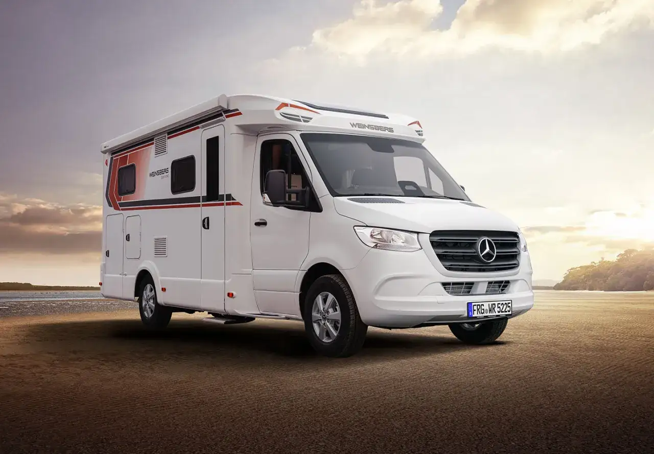 Un camping car profilé compact blanc, idéal pour explorer la côte au coucher du soleil.