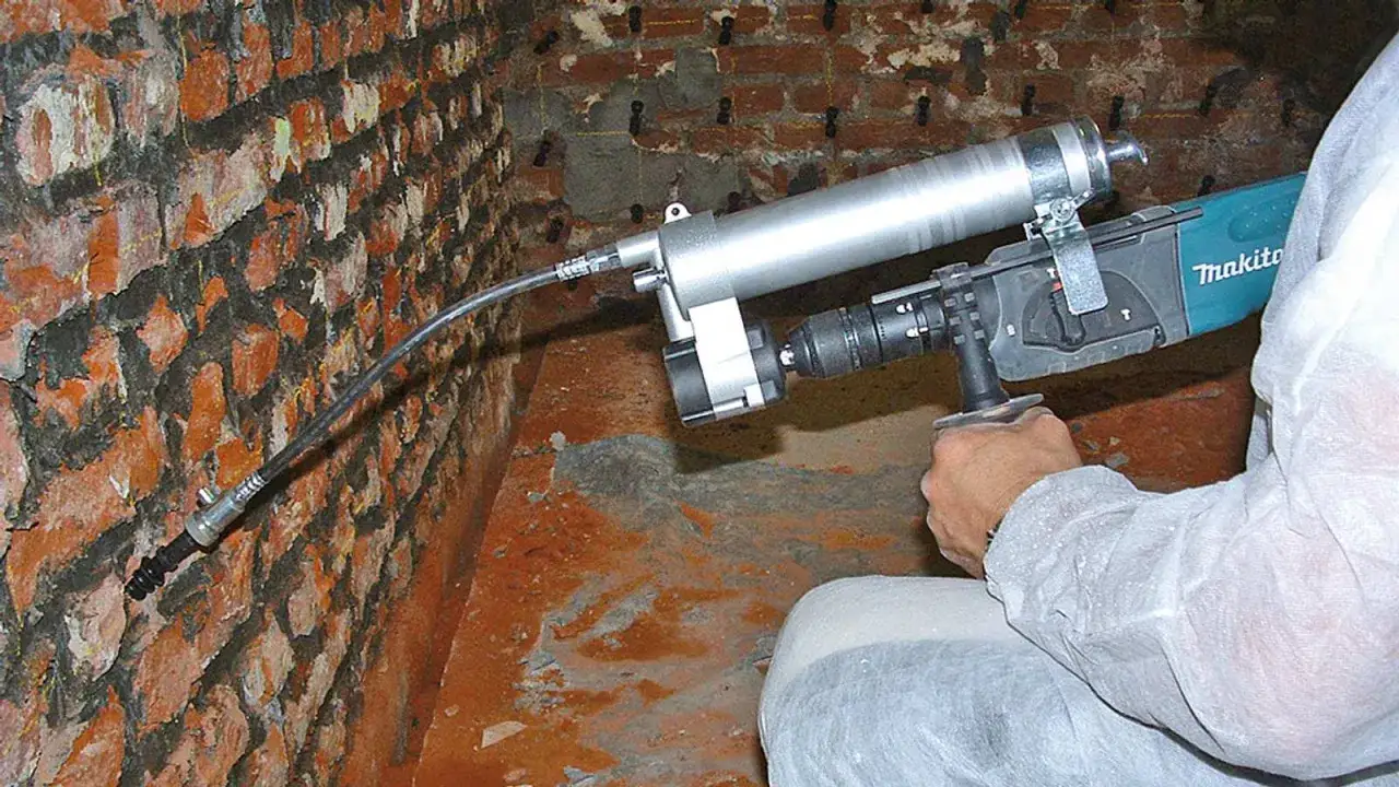 ATG Mauertrockenlegung: Ein Handwerker injiziert mit einem Gerät eine Flüssigkeit in eine feuchte Ziegelwand.
