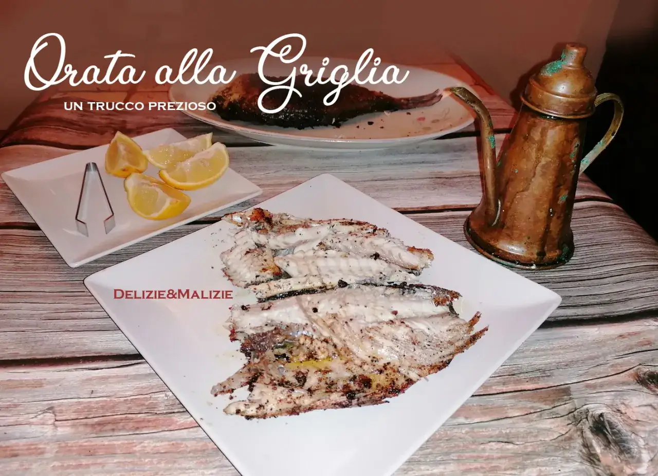 Orata alla griglia succulenta, servita con spicchi di limone e un'antica oliera in rame. Un piatto semplice ma delizioso.