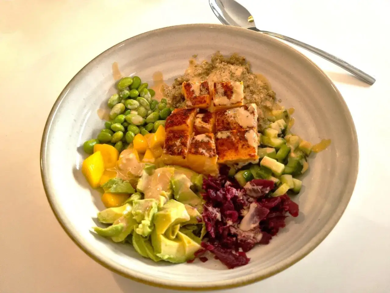 En färgstark bowl med lax, quinoa, edamamebönor, mango, avokado, rödbetor och gurka. Ett perfekt bowls recept för en hälsosam måltid.