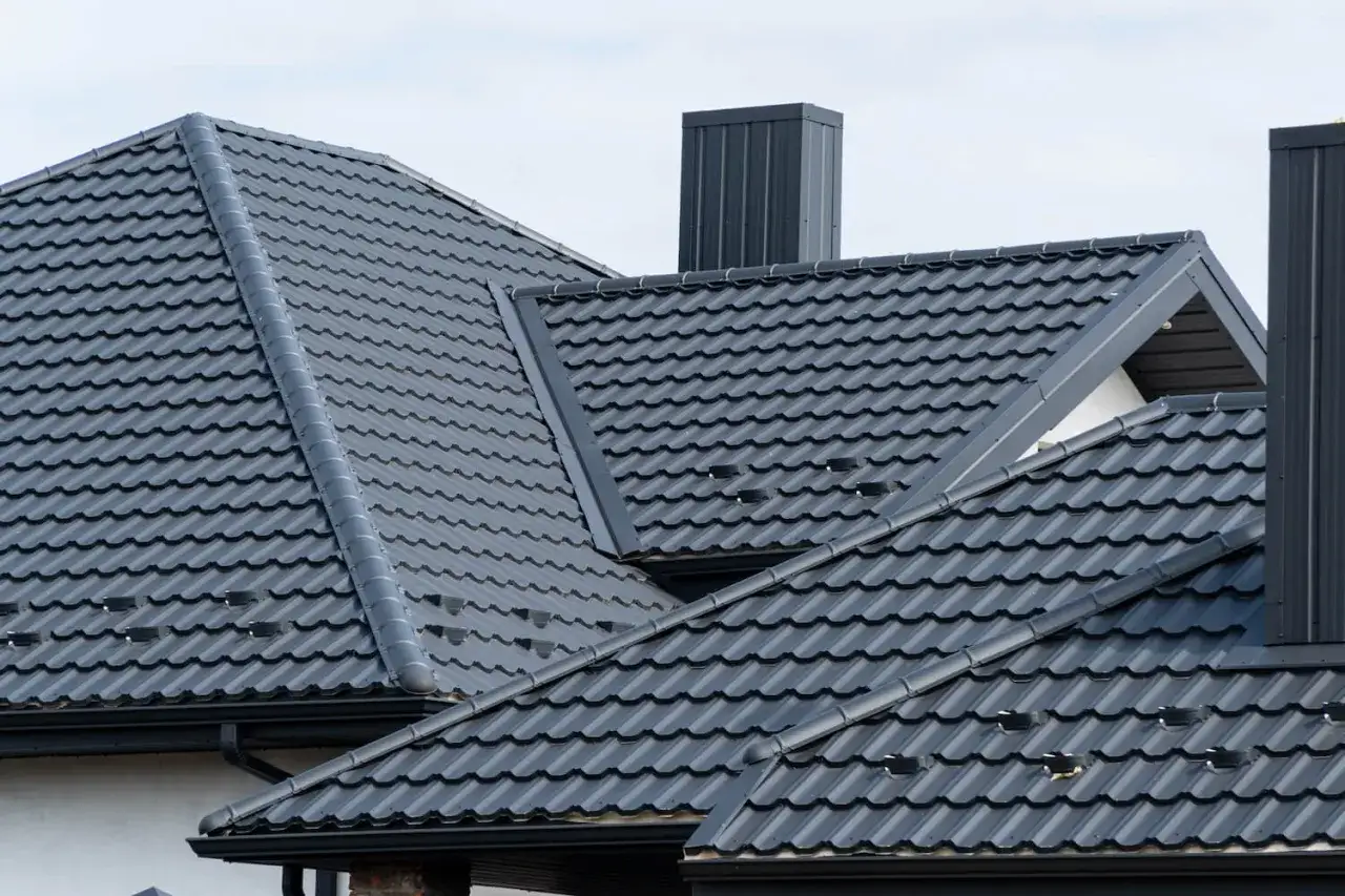 Dachziegel aus Metall bieten harte Bedachung und Brandschutz. Mehrere Schornsteine ragen aus dem modernen Dach hervor.