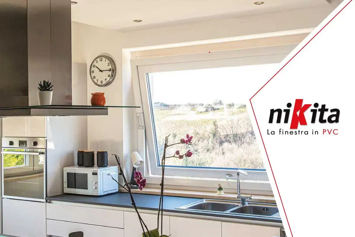 Interno cucina moderna con **casa con infissi bianchi** luminosa, lavello, microonde e vista sul paesaggio.
