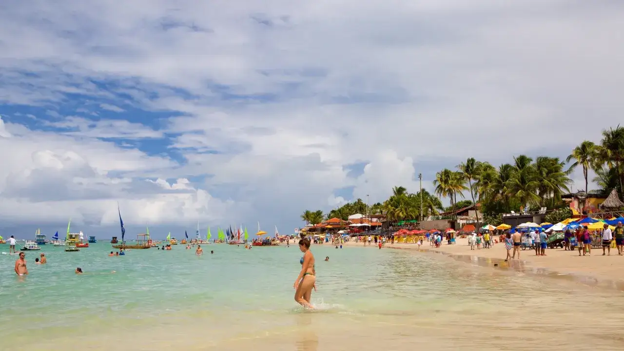 Sonniger Strand von Porto de Galinhas mit vielen Segelbooten, Palmen und Badeg&auml;sten.