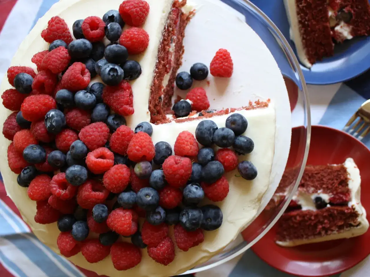 En saftig red velvet cake, toppad med färska hallon och blåbär, redo att avnjutas.