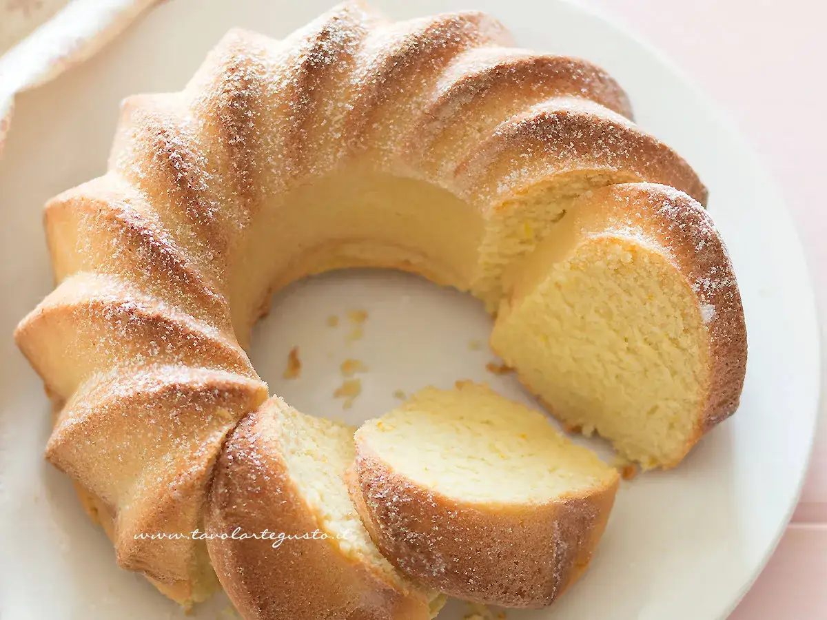 Torta alla ricotta veloce e morbidissima, spolverata di zucchero a velo, su un piatto bianco.