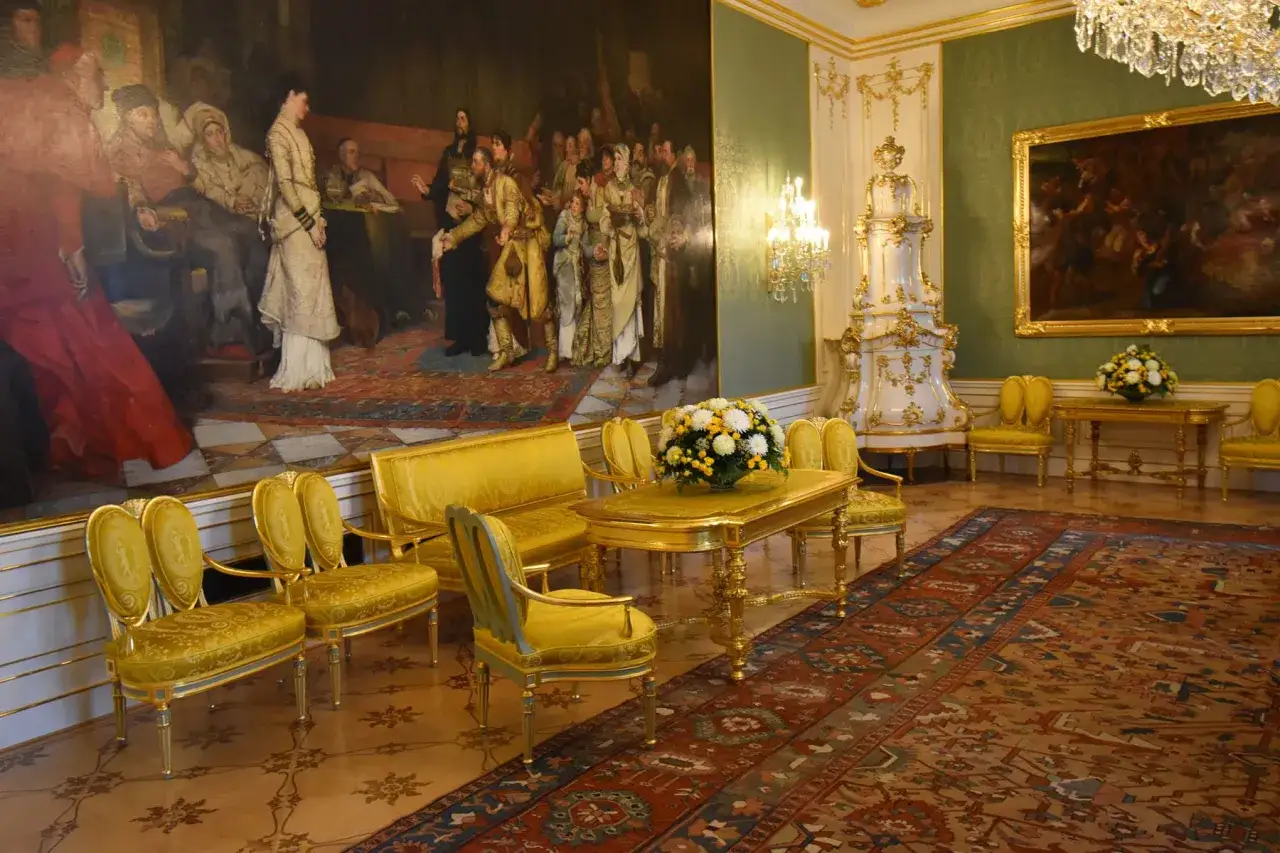 Salon dor&eacute; dans l'interieur du chateau de Prague, avec un grand tableau, des fauteuils et un lustre en cristal.