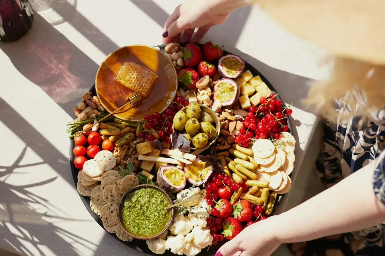 Plateau gourmand aux couleurs vives : fruits, fromages, olives, noix, et miel. Une invitation à la cuisine du terroir.