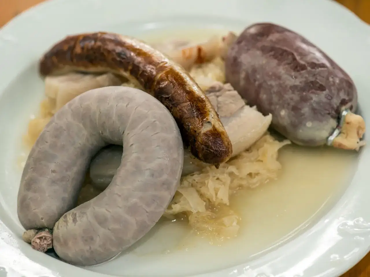 Bayerische Schlachtschüssel mit Blutwurst, Leberwurst und Bratwurst auf Sauerkraut.