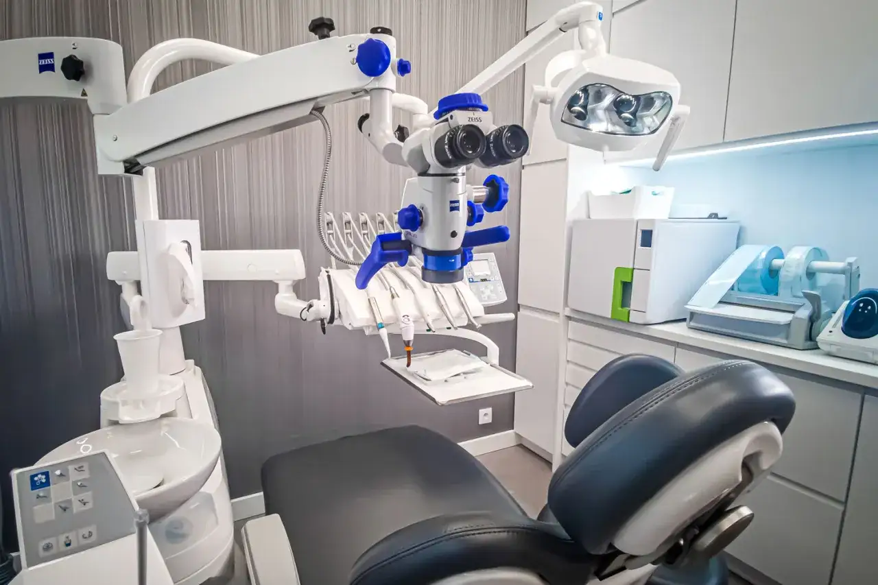 Nowoczesny gabinet stomatologiczny z fotelem, mikroskopem Zeiss i lampą zabiegową.