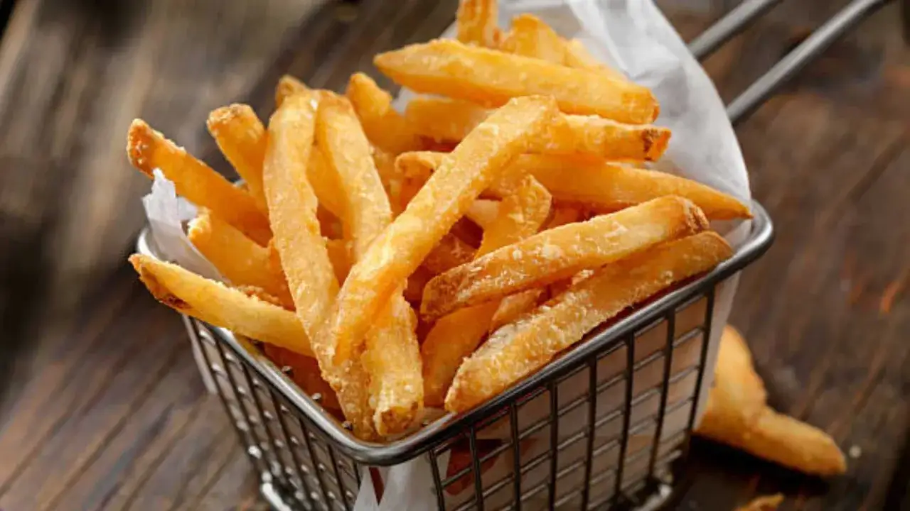 Cesta metálica llena de crujientes patatas fritas doradas, listas para disfrutar.