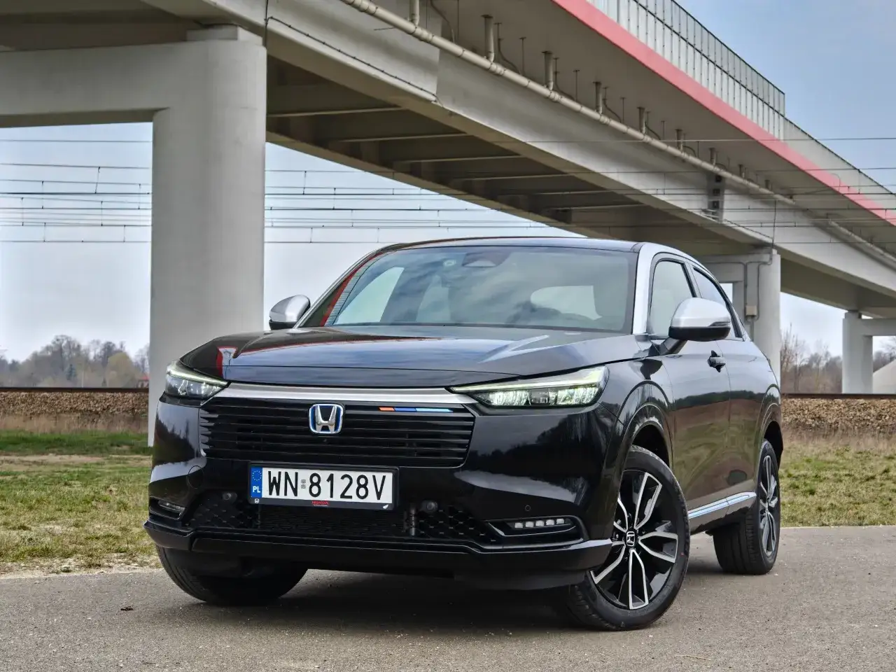 Czarny Honda HR-V z nowoczesnym designem stoi pod wiaduktem kolejowym.