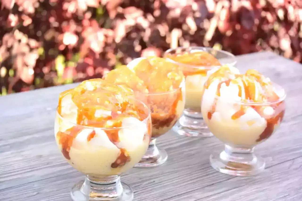 Quatre coupes de verrine remplies d'oeufs à la neige, nappés de caramel.