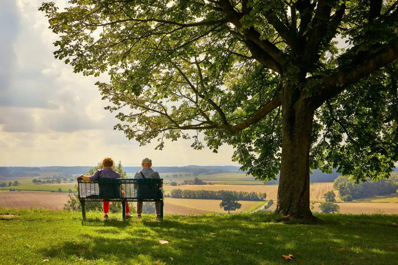 Ein Paar genießt die Aussicht auf die Landschaft bei Stromberg, Oelde, unter einem großen Baum.