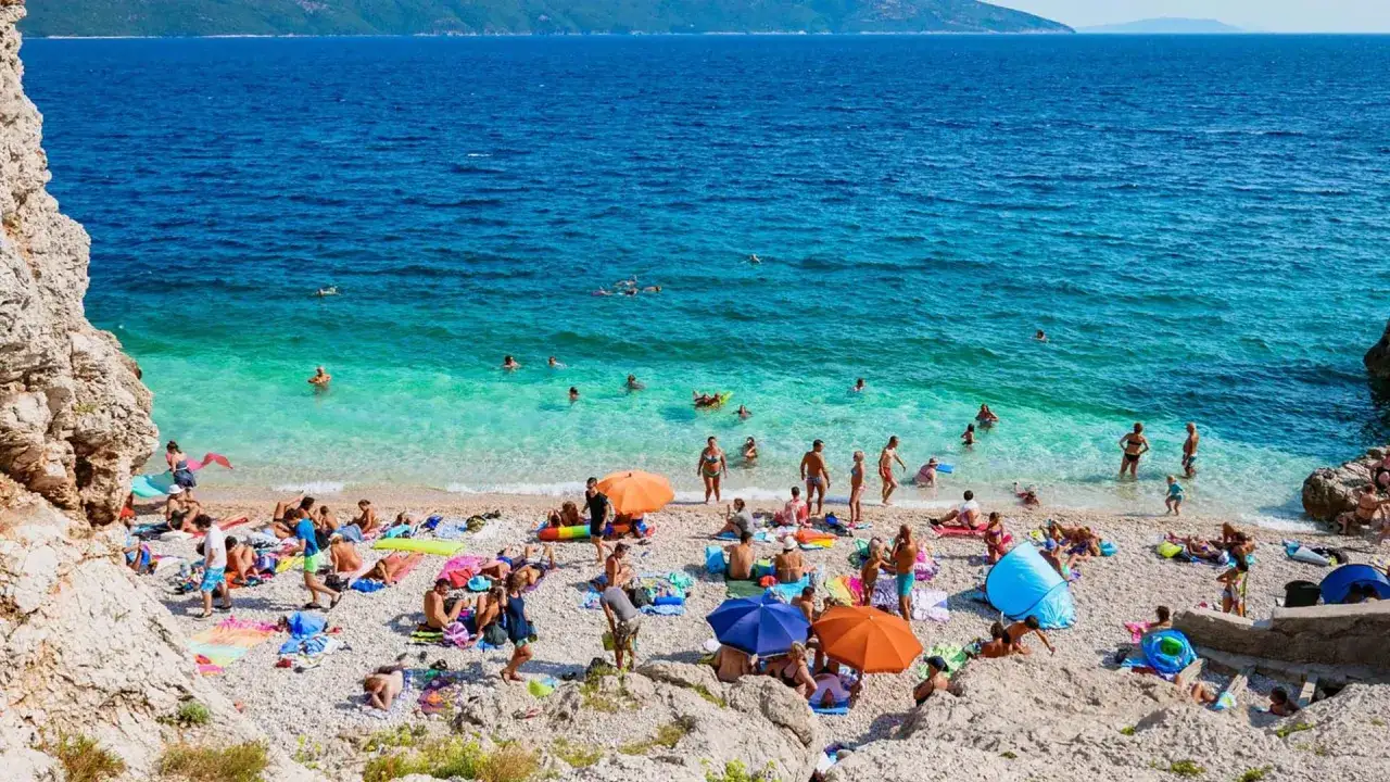 Idealna chorwacja pogoda lipiec: plaża pełna ludzi, turkusowa woda, słońce i relaks.