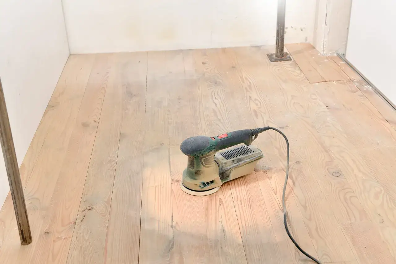 Ponceuse sur un parquet en bois clair, pr&ecirc;te pour la r&eacute;novation.