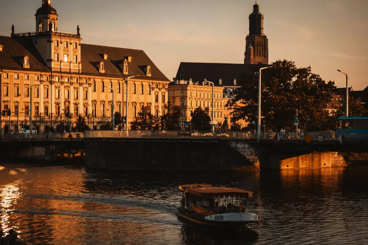 Idealna randka we Wrocławiu: rejs po Odrze przy zachodzącym słońcu, z widokiem na zabytkowe budynki i wieżę.