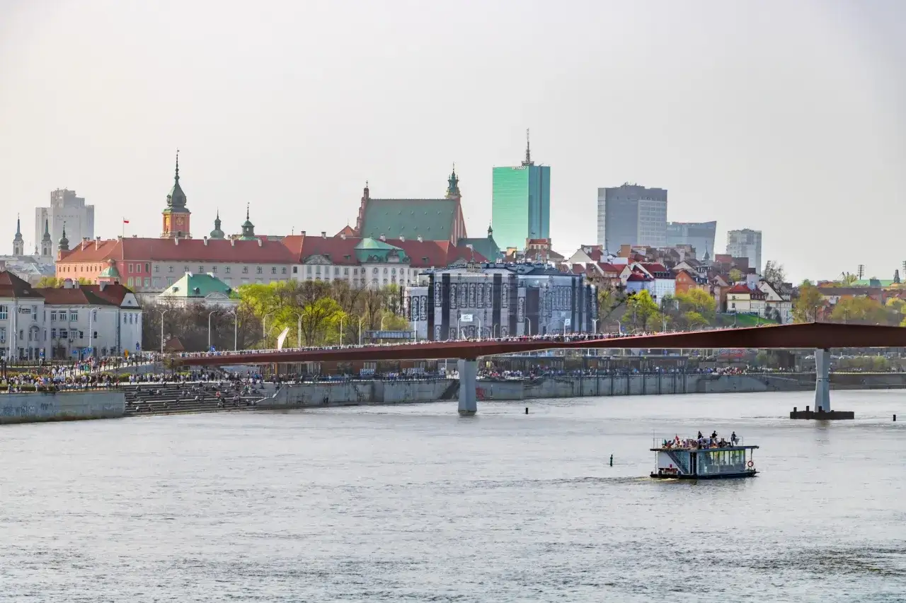 Widok na Wisłę i warszawską Starówkę z Zamkiem Królewskim. Na pierwszym planie statek wycieczkowy, a w tle most i miejska panorama. To jedne z fajnych miejsc w Warszawie.