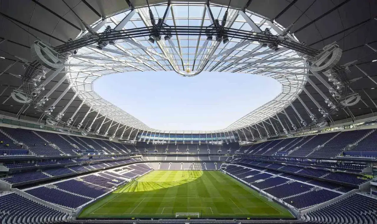Nowoczesny stadion w Anglii z imponującym, przeszklonym dachem. Puste trybuny czekają na kibiców.