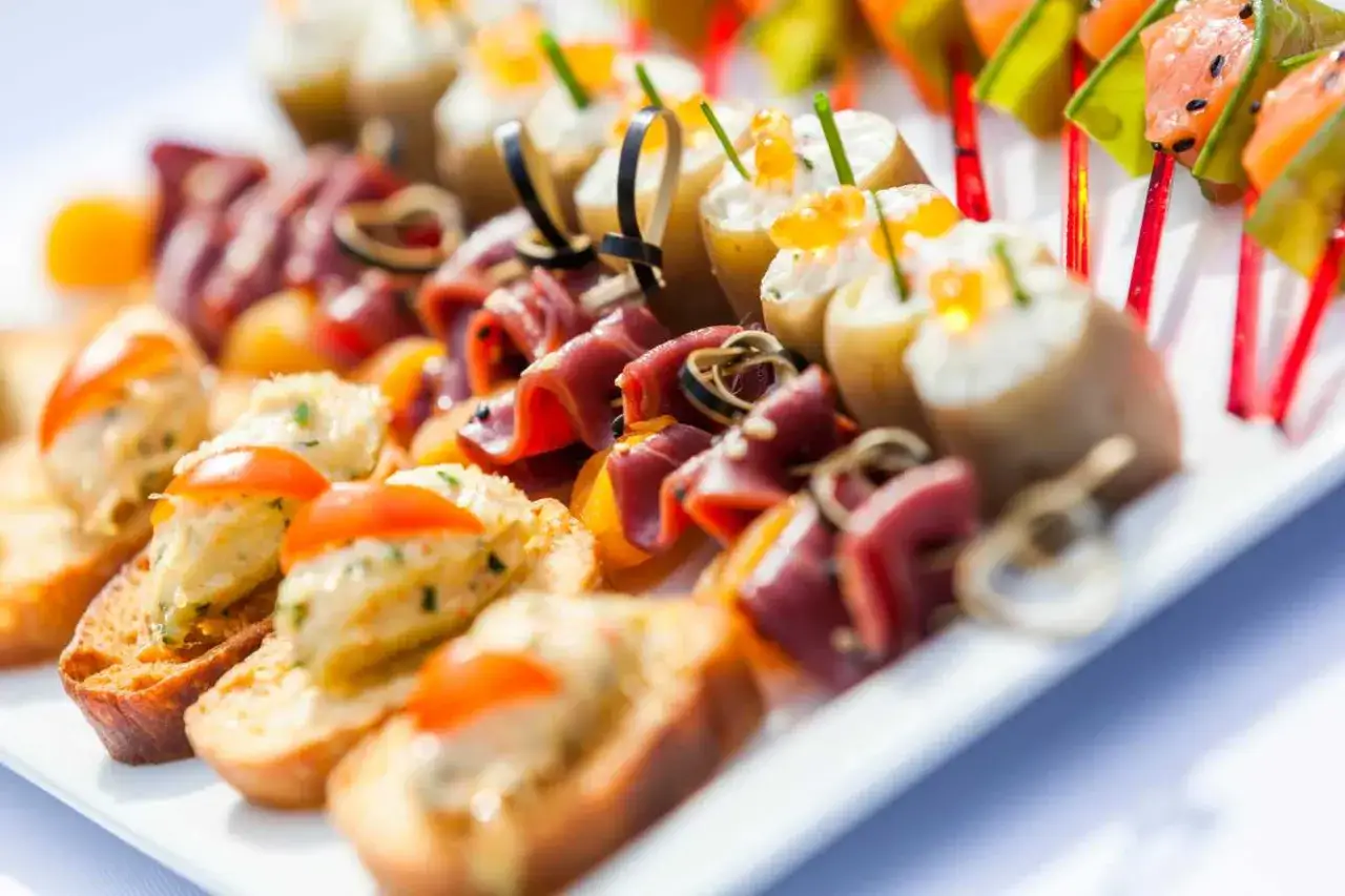 Plateau d'amuse-gueule froid à faire la veille : toasts, roulés de viande, mini-pommes de terre garnies de caviar et brochettes de saumon.