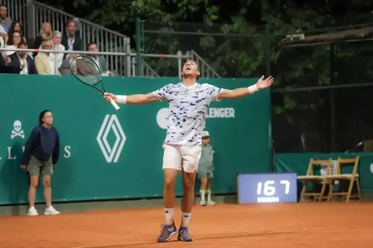Roberto Carballes Baena celebra un punto con los brazos extendidos en una cancha de tenis de tierra batida.