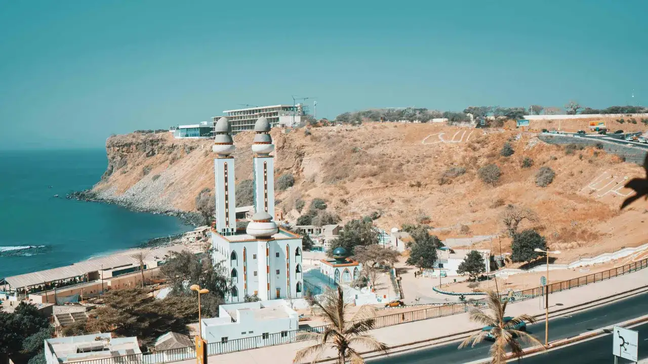 Wspaniałe senegal atrakcje: meczet z dwoma minaretami, klif nad oceanem i miasto w tle.