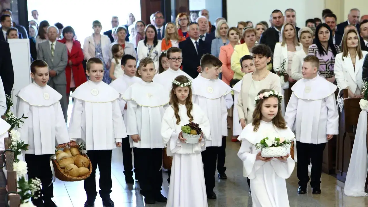 Dzieci w białych strojach komunijnych idą do kościoła. Zastanawiasz się, ile trwa komunia?