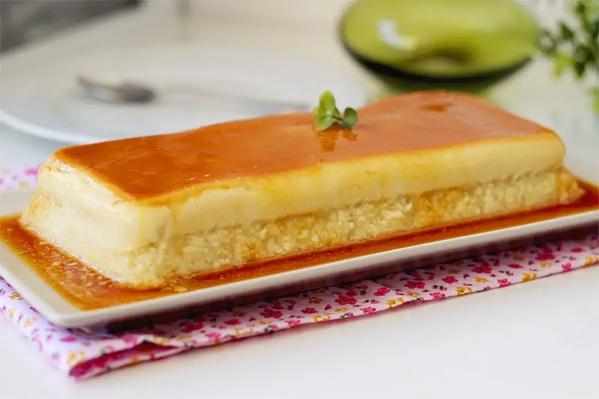 Delicioso flan de manzana rectangular, cubierto de caramelo dorado y decorado con una ramita verde.